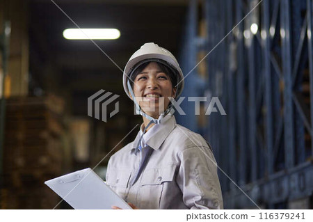 A woman in work clothes inspecting a factory 116379241