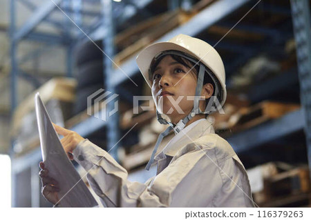 A woman in work clothes inspecting a factory A woman in work clothes inspecting a factory 116379263