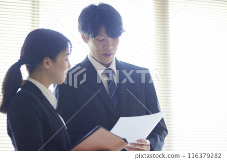 辦公室裡,男女職員一起閱讀文件。 辦公室裡,男女職員一起閱讀文件。 116379282