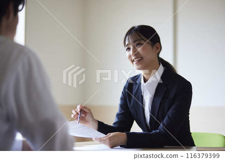 一位年輕的女職員在會議期間一邊發言一邊展示文件。 一位年輕的女職員在會議期間一邊發言一邊展示文件。 116379399