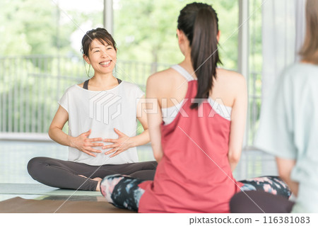 A female yoga teacher/instructor teaching yoga breathing techniques in a yoga class/Pilates 116381083