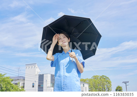 A woman using a parasol on a hot day A woman using a parasol on a hot day 116383035