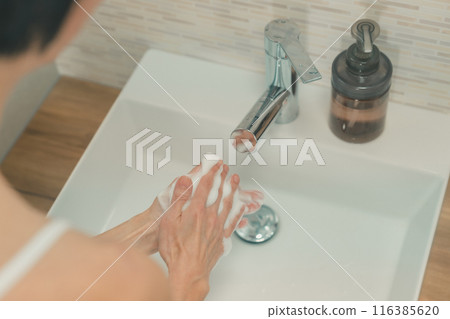 一位 50 多歲的婦女在家水槽裡洗手 116385620