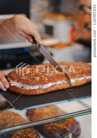 Close-up of a female baker's hands cutting a piece of coke leaf. Vertical Close-up of a female baker's hands cutting a piece of coke leaf. Vertical 116385932