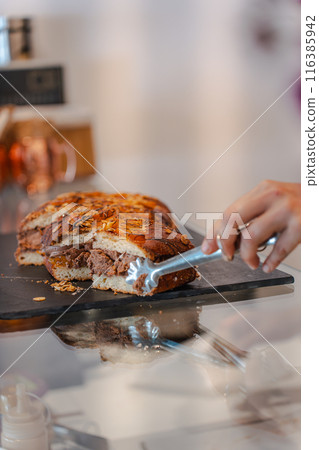 Baker picking up a piece of cake with tongs. Vertical Baker picking up a piece of cake with tongs. Vertical 116385942