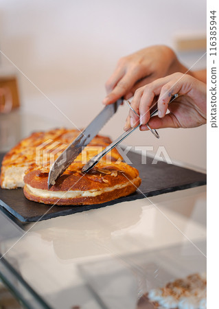 Woman's hands separating a traditional coke in a bakery. Vertical Woman's hands separating a traditional coke in a bakery. Vertical 116385944