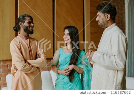 Indian colleagues dressed in patterned clothes smiling while having heated conversation in loft office 116387662