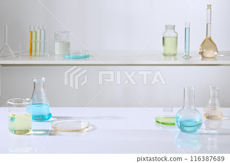 Front angle shot photo on the white background, two tiered shelves in laboratory displaying plenty of experiment glassware, which filled by colorful liquid. Blank space for product presentation 116387689