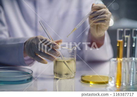 Laboratory theme photography with diagonal angle shot at the scene a scientist using a dropper to do experiment with yellow liquid. Space for adding text and elements of designing Laboratory theme photography with diagonal angle shot at the scene a scientist using a dropper to do experiment with yellow liquid. Space for adding text and elements of designing 116387717