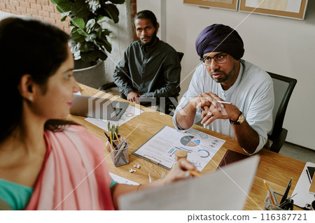 High angle shot of small group of young Indian startupers having heated discussion about last financial documents 116387721