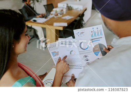 Over shoulder shot of coworkers discussing last annual income statement presented in colorful diagrams and graphics 116387823