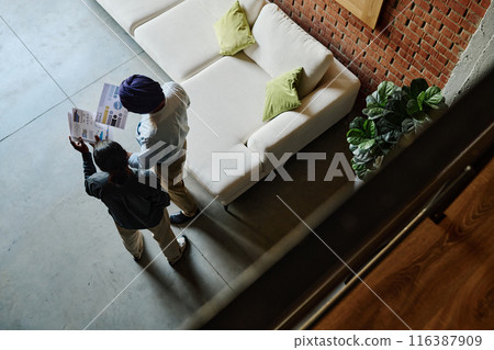 High angle shot of two colleagues holding papers with analysis and colorful diagrams and discussing it in office lobby 116387909
