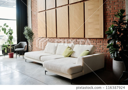 Roomy waiting zone in office made in loft style, zone equipped with ficuses in clay pots and white suede sofa and light suede armchair Roomy waiting zone in office made in loft style, zone equipped with ficuses in clay pots and white suede sofa and light suede armchair 116387924