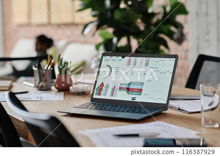Wooden work desk with black matt laptop demonstrating analytical research presentation, table full of papers and office supplies Wooden work desk with black matt laptop demonstrating analytical research presentation, table full of papers and office supplies 116387929
