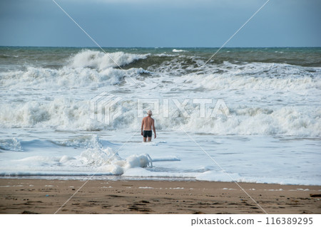A man alone swims in the Atlantic Ocean in a storm, big waves, danger on the beach A man alone swims in the Atlantic Ocean in a storm, big waves, danger on the beach 116389295