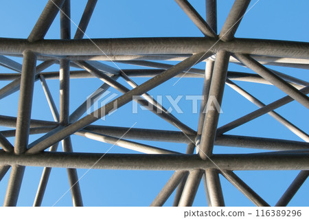 Abstract metal figure on a colorful pink background, artistically welded metal pipes, fragment of scaffolding in NYC Abstract metal figure on a colorful pink background, artistically welded metal pipes, fragment of scaffolding in NYC 116389296