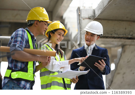Team of engineer and architects in safety hard hats discussing about new project plan at construction site 116389393
