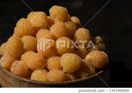 Yellow raspberries in a wooden bowl on the table. Summer berry. Vitamin food, berry harvest. Healthy nutrition 116390609