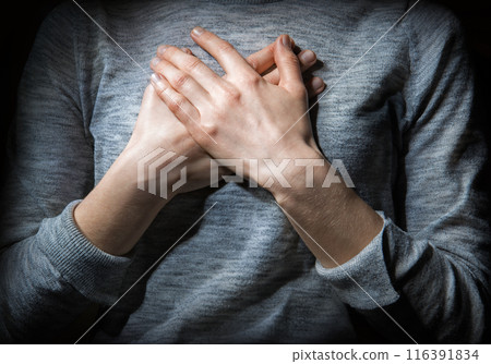 Hands folded in prayer over the heart 116391834