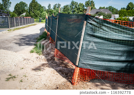 Fence around the construction site with cover against construction dust 116392778