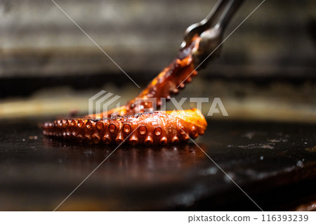 Close-up cooking an octopus tentacle on a restaurant griddle Close-up cooking an octopus tentacle on a restaurant griddle 116393239