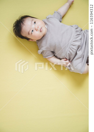 Baby lying on a yellow floor Baby lying on a yellow floor 116394312