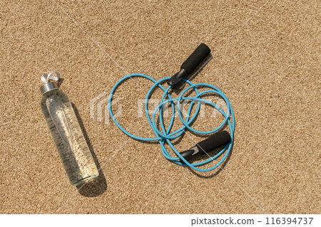 Sports set of water and jump rope for workout and activity on outdoor sports ground. View from above. 116394737