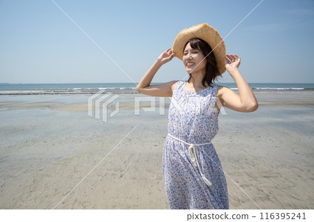 A smiling woman wearing a straw hat standing on the beach (Yuigahama, Kanagawa Prefecture) A smiling woman wearing a straw hat standing on the beach (Yuigahama, Kanagawa Prefecture) 116395241