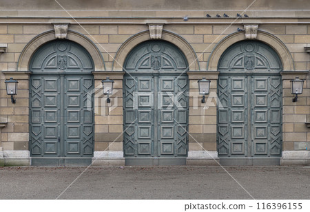 Facade of arched iron doorway with lamps on stone wall of The Munich Residence Building. 116396155