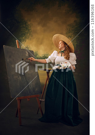 Woman in historical attire, large straw hat, white blouse, and green velvet skirt, stands at easel painting with palette in hand, against vintage background Woman in historical attire, large straw hat, white blouse, and green velvet skirt, stands at easel painting with palette in hand, against vintage background 116396168