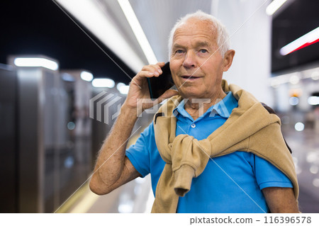Elderly man talking on phone in subway station Elderly man talking on phone in subway station 116396578