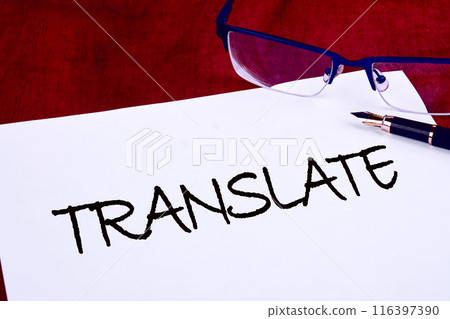 Concept of online translation from foreign language. Translate text on white paper on a mahogany table Concept of online translation from foreign language. Translate text on white paper on a mahogany table 116397390