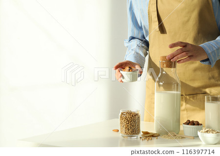 Man, bottle of alternative milk and herbal ingredients on light background, space for text Man, bottle of alternative milk and herbal ingredients on light background, space for text 116397714
