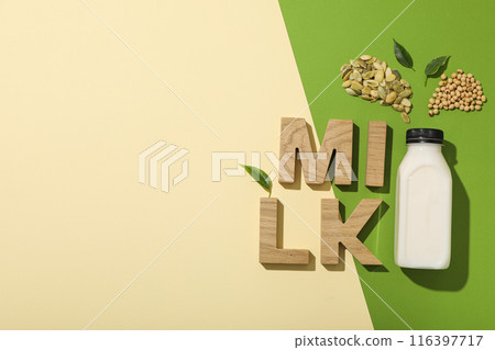 Bottle of alternative milk and wooden letters on beige and green background, space for text 116397717