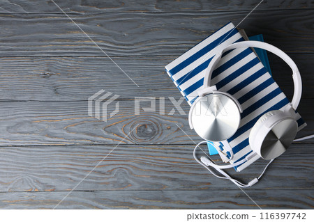 Books with modern headphones, on a gray background. 116397742