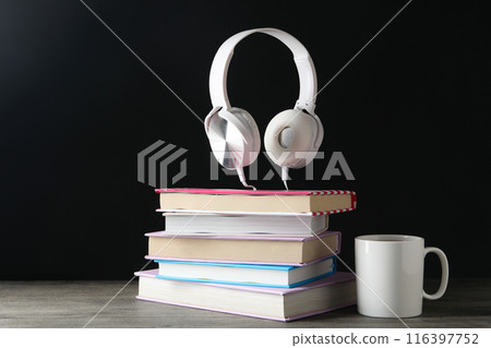 Books with modern headphones, on a dark background. 116397752