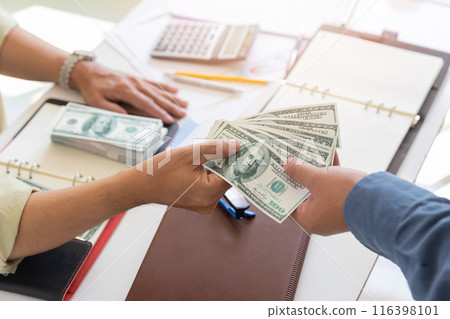 Man offering batch of hundred dollar bills. Hand of a businessman giving money to his partner. Hand receiving money from businessman. Venality, bribe, corruption concept. 116398101