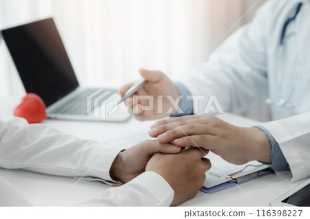 Doctor holding patient's hand for encouragement, empathy, cheering and support while medical examination. Bad news lessening, medicine and health care concept. Doctor holding patient's hand for encouragement, empathy, cheering and support while medical examination. Bad news lessening, medicine and health care concept. 116398227