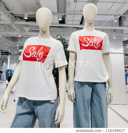 Two mannequins are dressed in white and blue clothing with a red SALE sign on their shirts 116399427