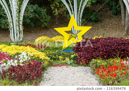 yellow star next to a flowerbed of flowers on green grass 116399476