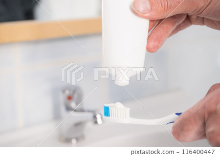 Person putting toothpaste on toothbrush 116400447