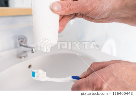 Person putting toothpaste on toothbrush 116400448
