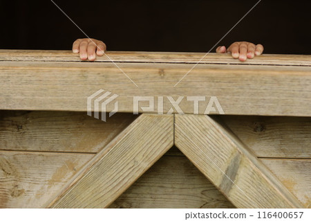 A wooden structure with two hands peeking out from behind it A wooden structure with two hands peeking out from behind it 116400657
