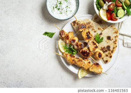 Chicken souvlaki kebabs with flatbread and greek salad 116401563