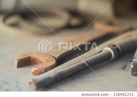 Locksmith tools such as a wrench and an adjustable wrench with selective focus lie on a beige surface and gather dust idle. 116402252