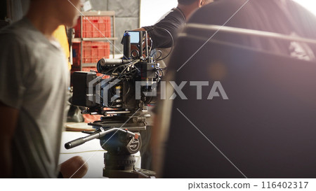 Film director and crew making commercial content advertising in studio. Filmmaker crew team with professional cinema equipment and video camera on the set. Technique of modern filming and advertising. Film director and crew making commercial content advertising in studio. Filmmaker crew team with professional cinema equipment and video camera on the set. Technique of modern filming and advertising. 116402317