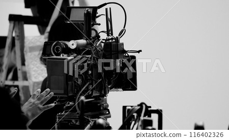 Film director and crew making commercial content advertising in studio. Filmmaker crew team with professional cinema equipment and video camera on the set. Technique of modern filming and advertising. 116402326