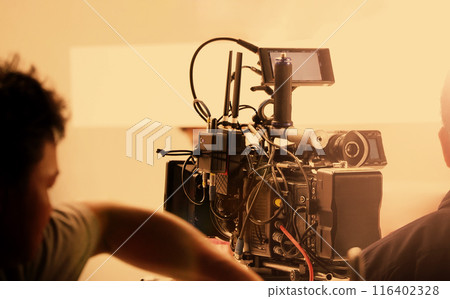 Film director and crew making commercial content advertising in studio. Filmmaker crew team with professional cinema equipment and video camera on the set. Technique of modern filming and advertising. Film director and crew making commercial content advertising in studio. Filmmaker crew team with professional cinema equipment and video camera on the set. Technique of modern filming and advertising. 116402328