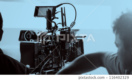 Film director and crew making commercial content advertising in studio. Filmmaker crew team with professional cinema equipment and video camera on the set. Technique of modern filming and advertising. 116402329