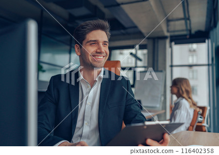 Businessman sitting at desk with clipboard and thinking about a new project on colleague background 116402358